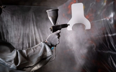 Imagem de um homem pintando uma peça, simbolizando a precisão e excelência dos serviços oferecidos pela nossa empresa.